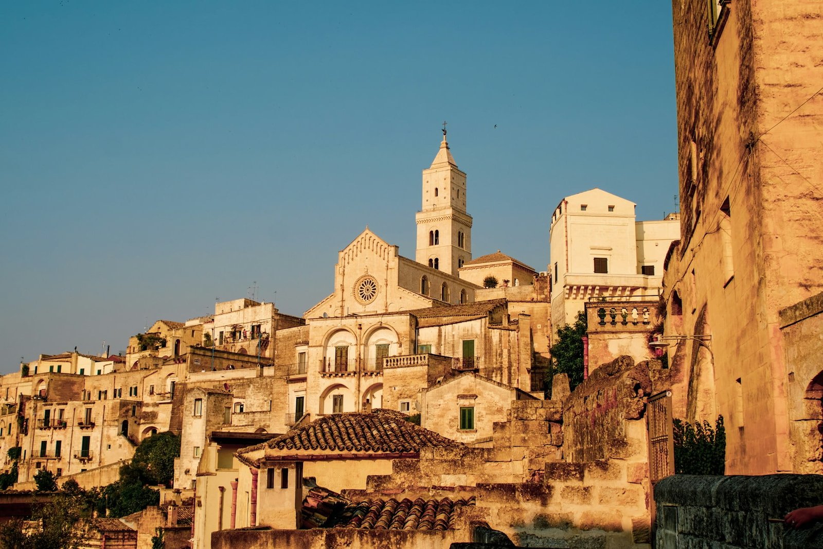 A hillside village with stone buildings and a prominent bell tower bathed in warm sunlight under a clear sky, this hidden gem is one of the most underrated European destinations.