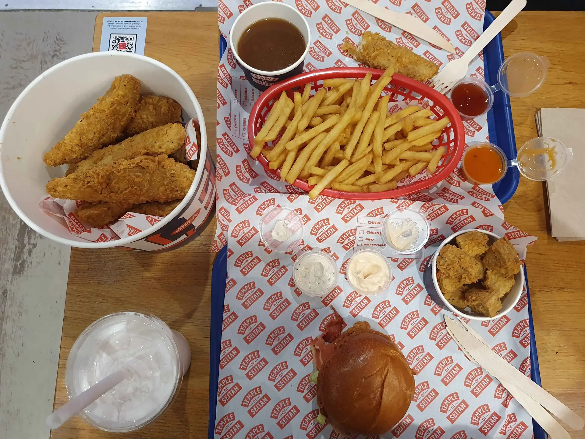 A table at one of the Best Vegan Spots with a variety of plant-based foods, including vegan chicken tenders, a burger, crispy fries, fried cauliflower bites, and drinks.