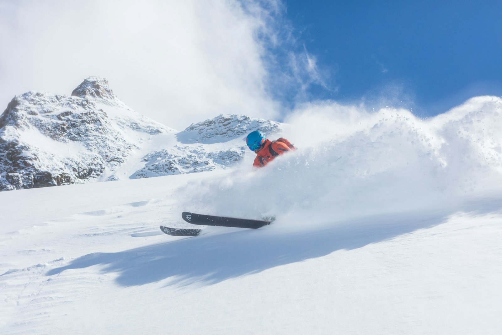 Winter sports destinations in Europe A skier in bright clothes goes down a snowy hill fast, with snowy mountains in the background, showing the fun of winter sports destinations in Europe