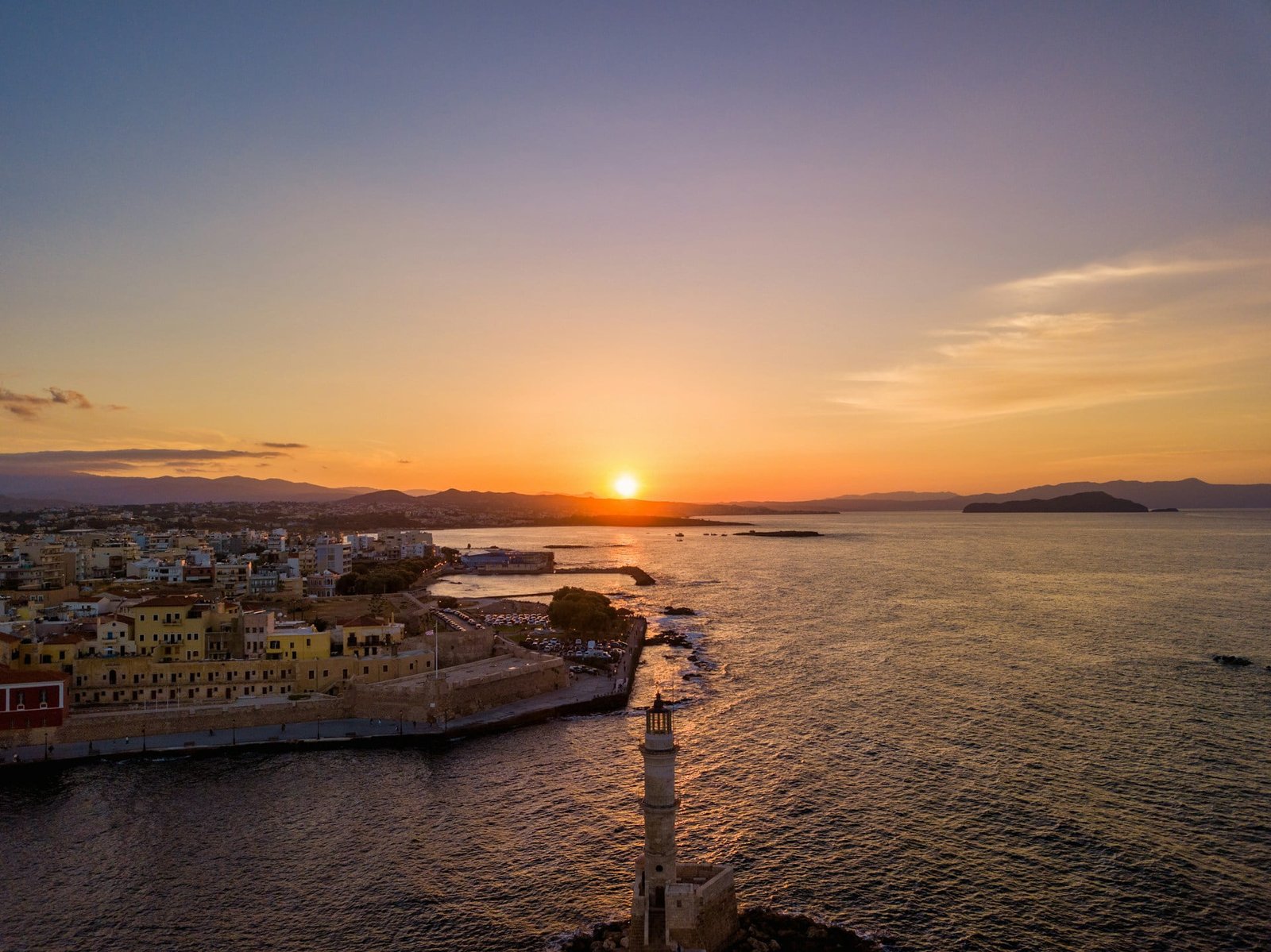 A serene sunset view over the Old Venetian Port of Chania, Agiou Markou, Chania, Greece, with warm hues reflecting on calm waters despite being labeled as the “worst time to visit Greece.”