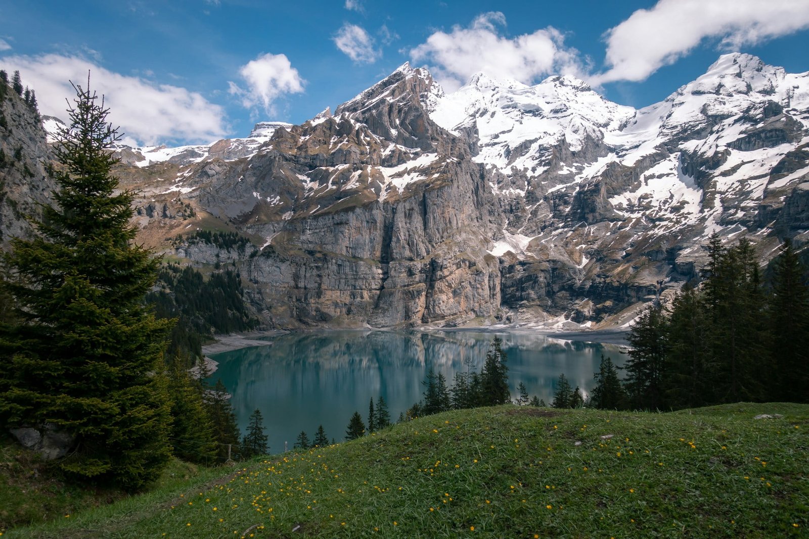 Breathtaking view of Oeschinen Lake in Switzerland, surrounded by majestic snow-capped mountains and lush greenery, inviting travelers to plan a trip to Switzerland and explore its natural beauty.