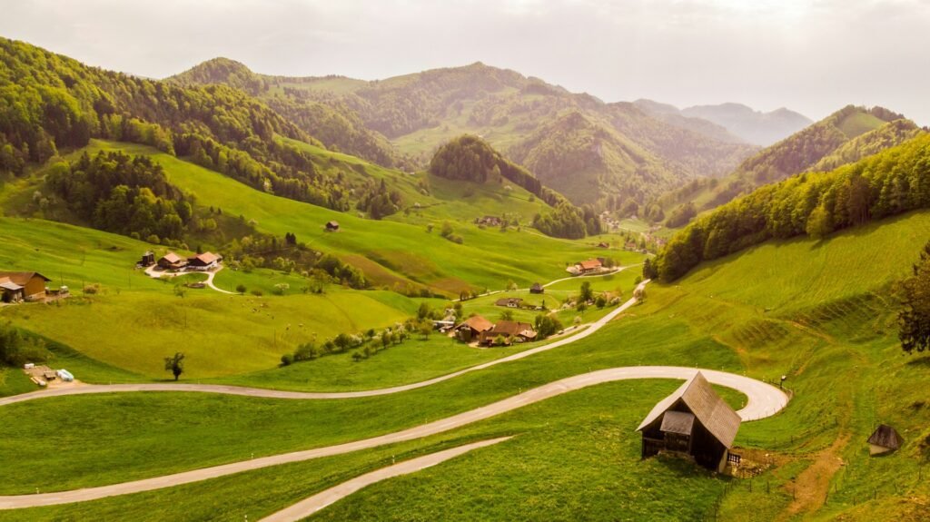 A serene view of Passwang Pass in Mümliswil-Ramiswil, Switzerland, showcasing lush green hills and a winding road amidst the vibrant landscape, epitomizing the best time of the year to visit Switzerland.