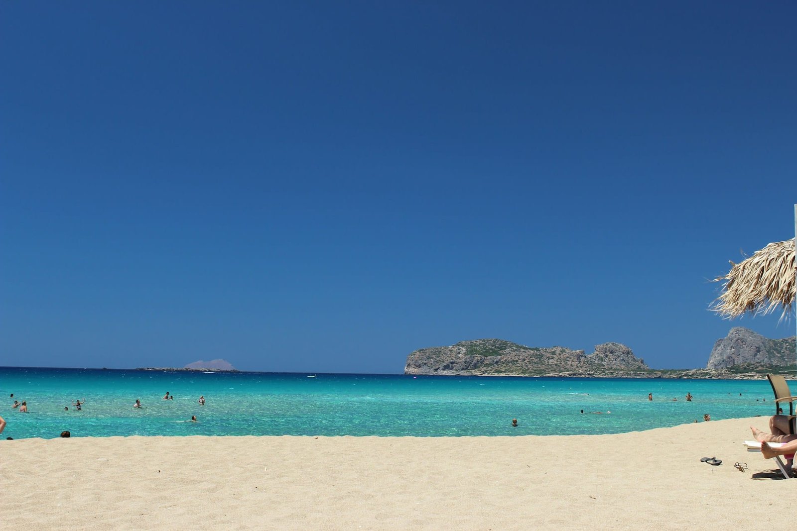 Visiting Greece for the first time, a beautiful beach in Crete with clear blue water and people enjoying the sun.