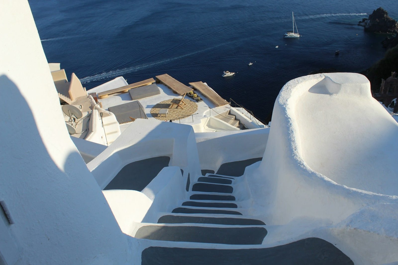 A view of Santorini, one of the top Greece cities to visit, with white buildings and blue roofs overlooking the sea.