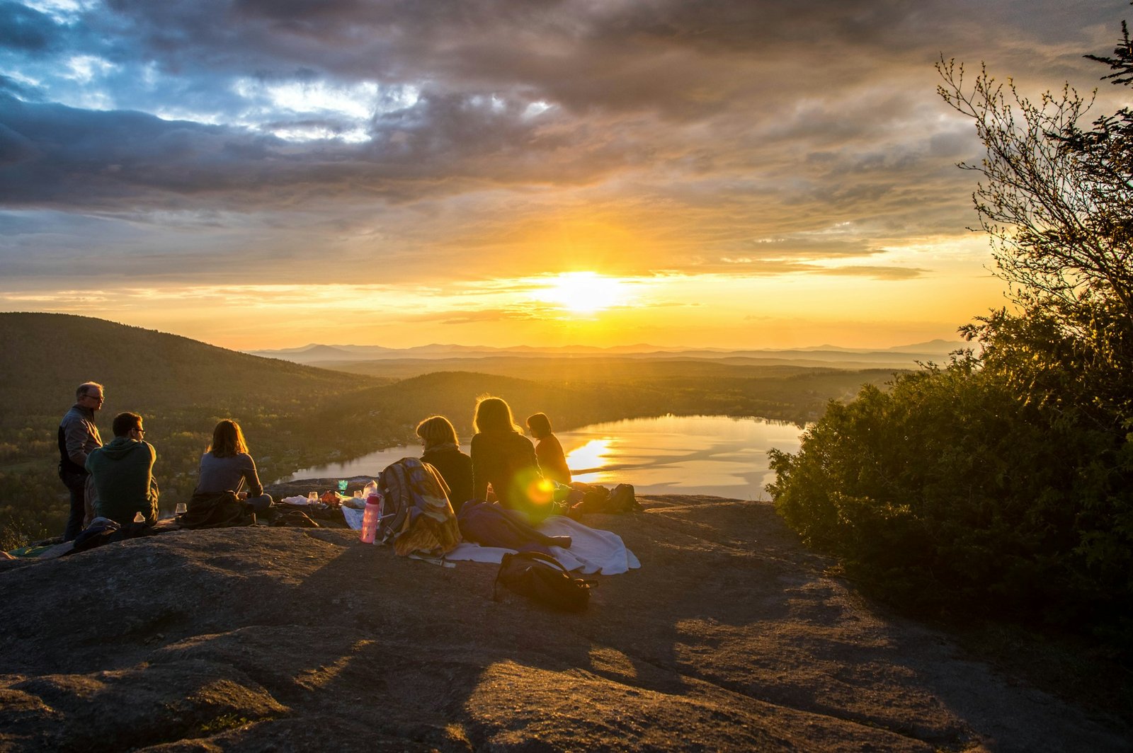 Group enjoying a sunset picnic on a mountain as part of budget-friendly European travel tips