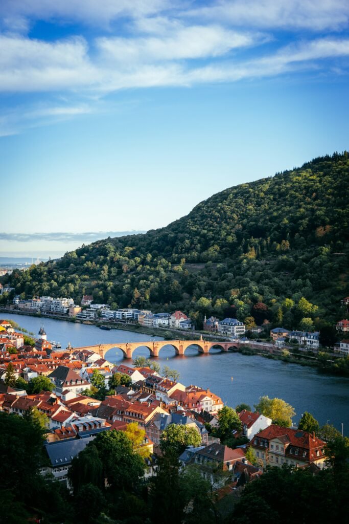 Destinations Heidelberg’s Old Bridge spanning the Neckar River at sunset, framed by historic buildings and scenic hills.